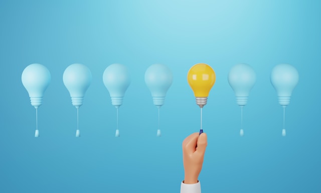 image of a series of light bulbs with strings and a hand reaching out to one that is illuminates in yellow while the rest are off