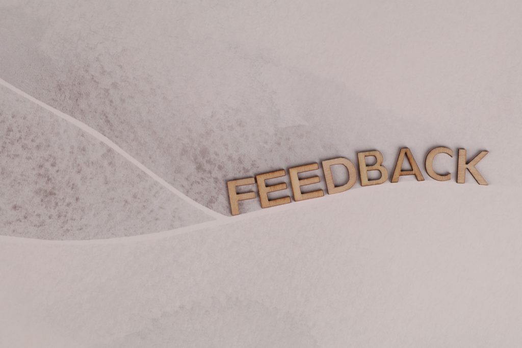 feedback written using wooden letters across a beige textured background