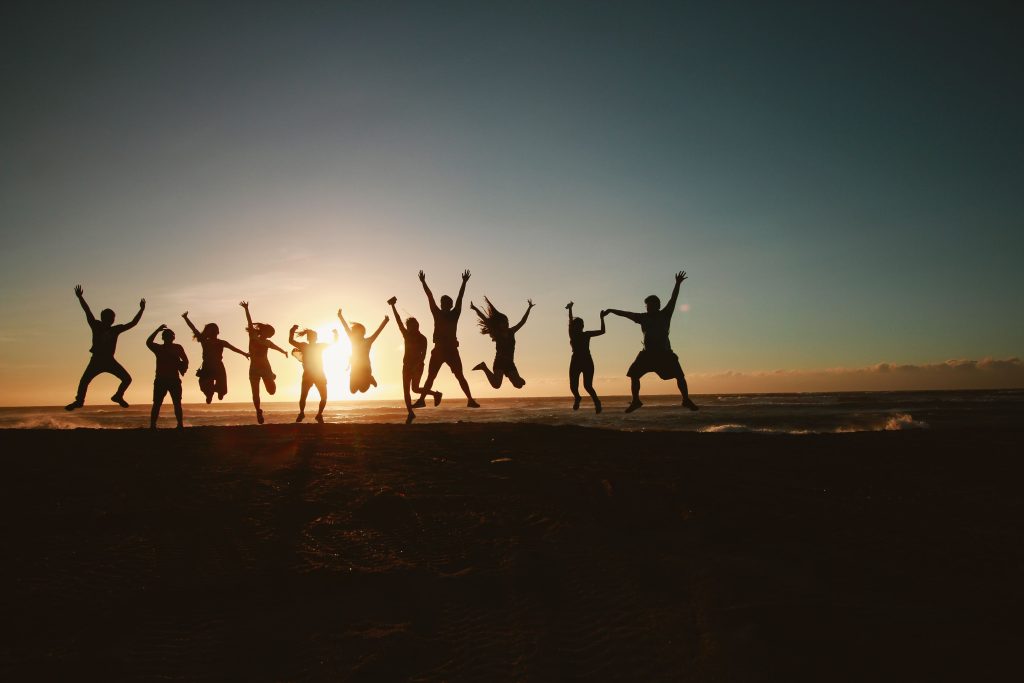 people jumping in the air with the sunsetting behind them